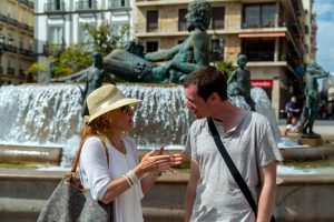 Tour guide Kate explains architecture to traveler in the Plaza de la Virgen in Valencia, Spain.